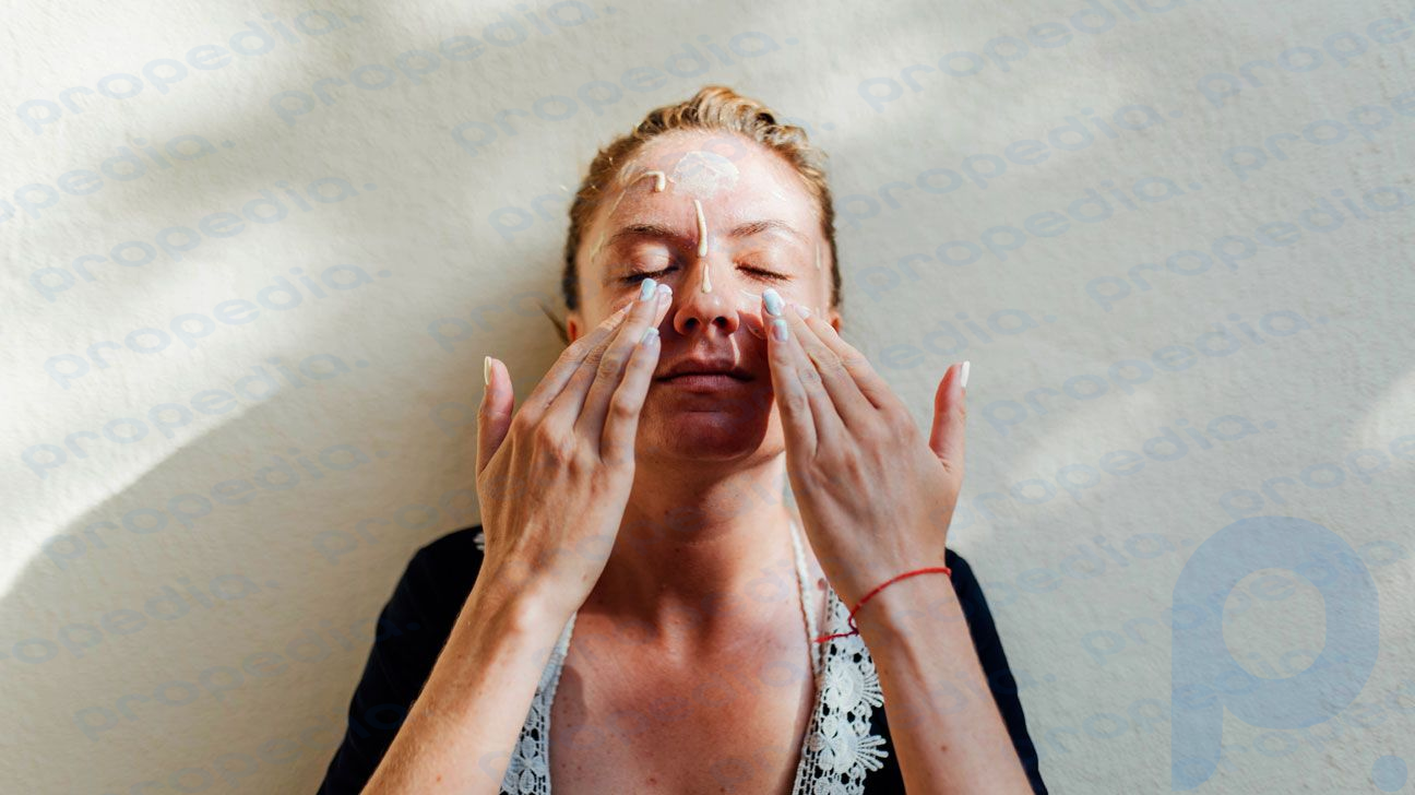 Frau trägt Feuchtigkeitscreme auf ihr Gesicht auf.
