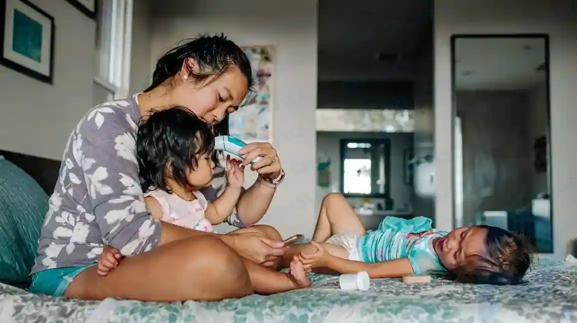 Madre tomando la temperatura de un niño que tuvo una convulsión febril.