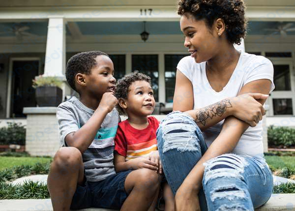 Eine Mutter spricht mit ihren beiden kleinen Kindern am Bordstein vor ihrem Haus in Atlanta, Georgia.  Eltern, Sohn, Tochter