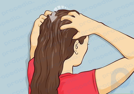 Étape 3 Trempez le bout de vos doigts dans l'huile tiède et appliquez l'huile sur les racines des cheveux en effectuant des mouvements circulaires.