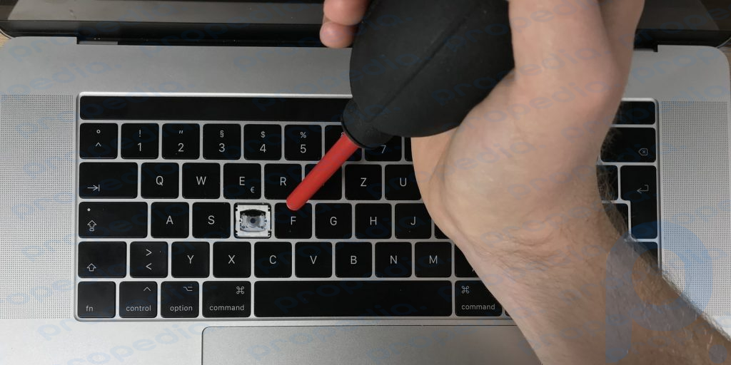 Blasen Sie Staub von den MacBook-Tasten